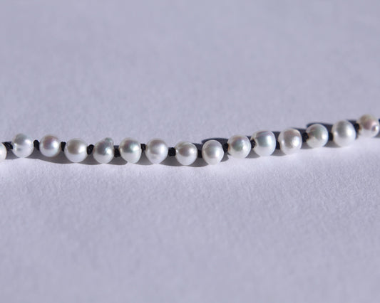 Zoom sur les perles et les noeuds de soie noir entre chaque perles