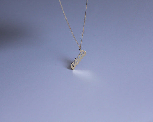 collier avec un pendentif en laiton doré portant le mot "acab" dessus