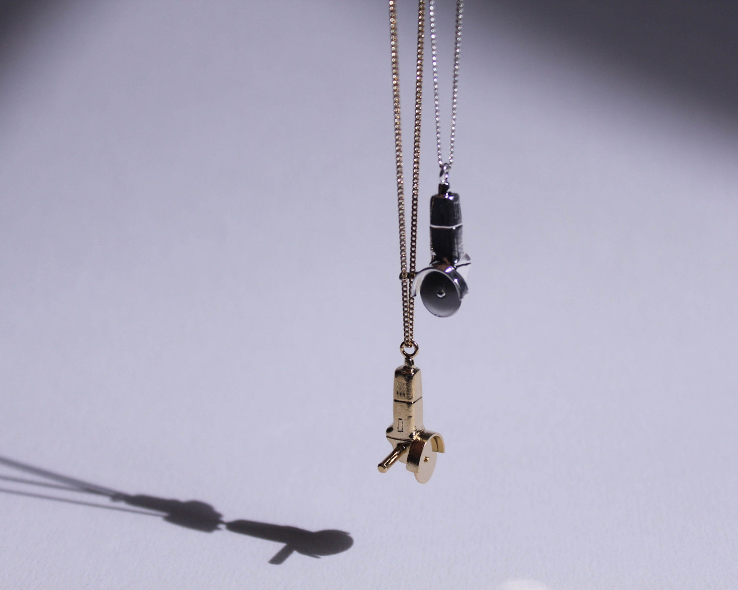 des pendentifs en argent massif et en laiton plaqué or représentant des meuleuses avec la lame qui tourne