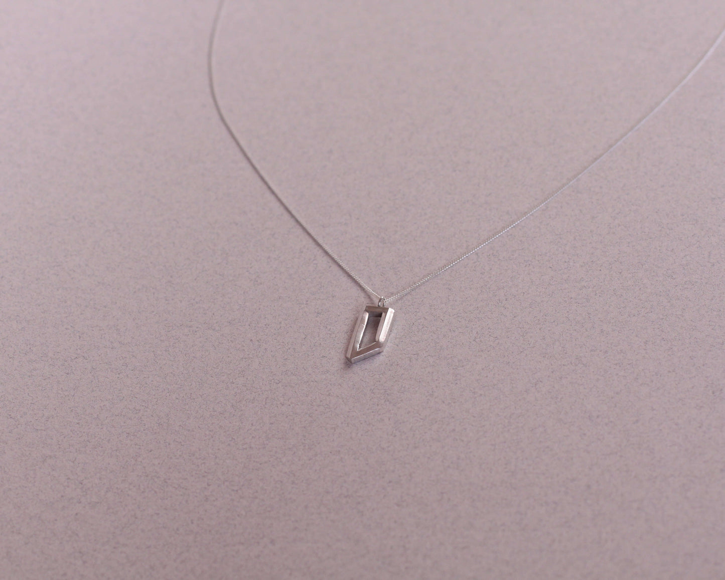 collier avec un pendentif en argent massif en forme d'objet impossible