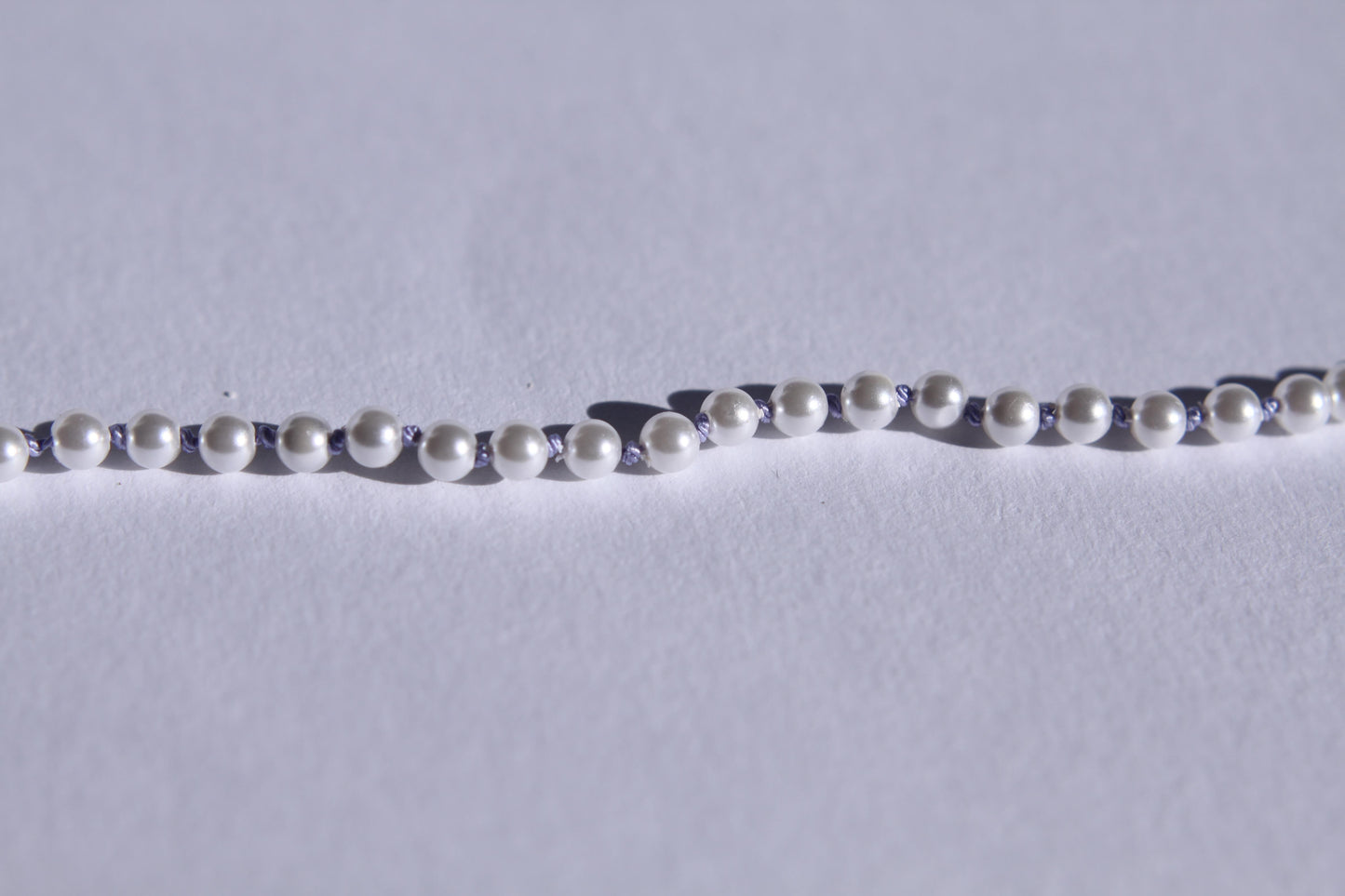 Zoom sur les perles et les noeuds de soie lila entre chaque perles