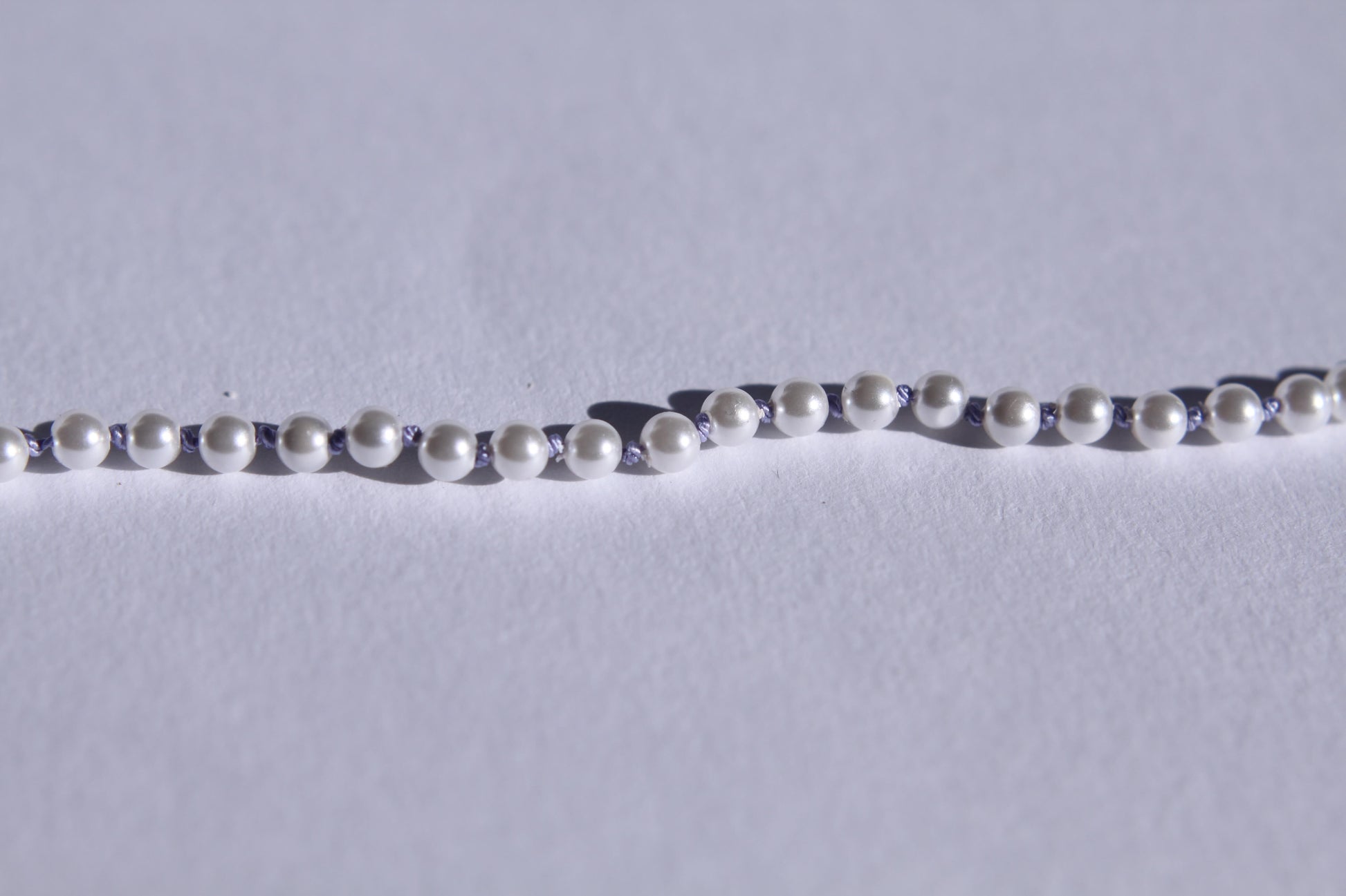 Zoom sur les perles et les noeuds de soie lila entre chaque perles