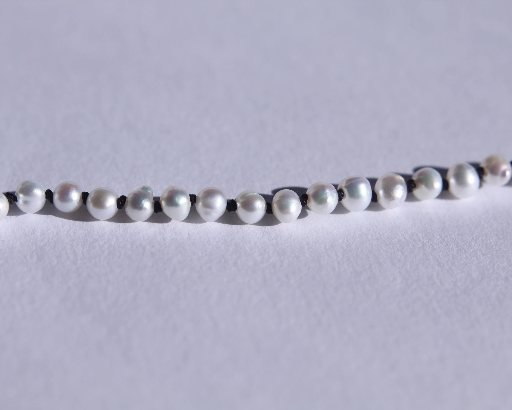 Zoom sur les perles et les noeuds de soie noir entre chaque perles