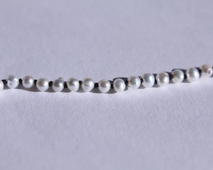 Zoom sur les perles et les noeuds de soie noir entre chaque perles