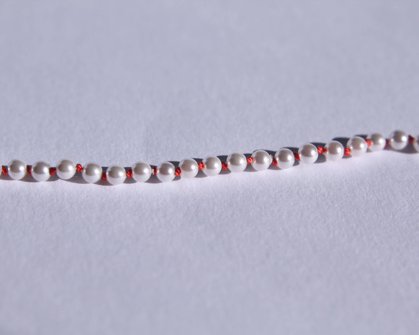 Zoom sur les perles et les nœuds de soie orange entre chaque perles