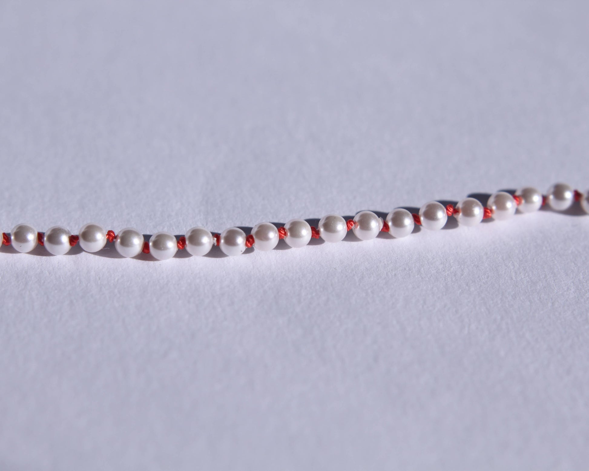 Zoom sur les perles et les nœuds de soie orange entre chaque perles