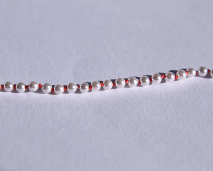 Zoom sur les perles et les nœuds de soie orange entre chaque perles