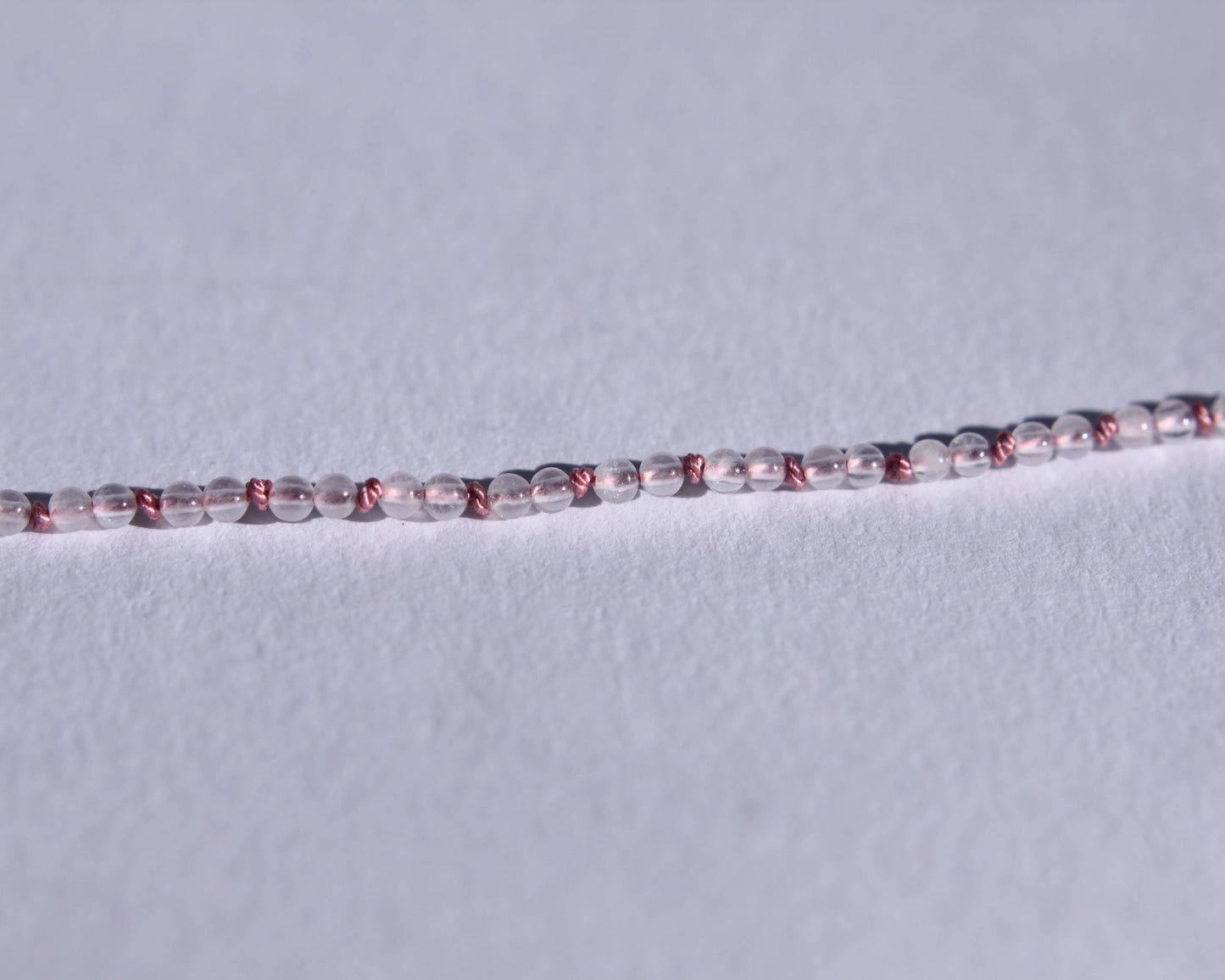 zoom sur les perles en quartz rose et les nœuds en soie