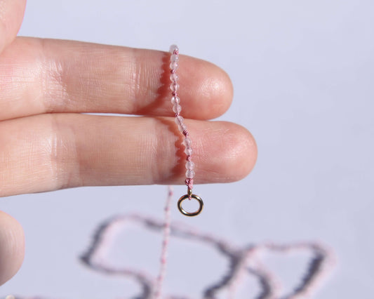 bout du collier de perles en quartz rose tenu sur une main 