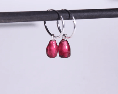 zoom sur une paire de boucles d'oreilles en argent représentant des arilles de grenade