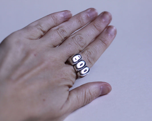 bague évoquant l'expression "BOO" en argent massif portée au doigt