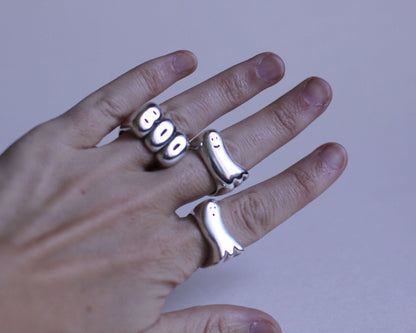 série de bagues en argent massif portées représentant des fantômes et l'expression "BOO"