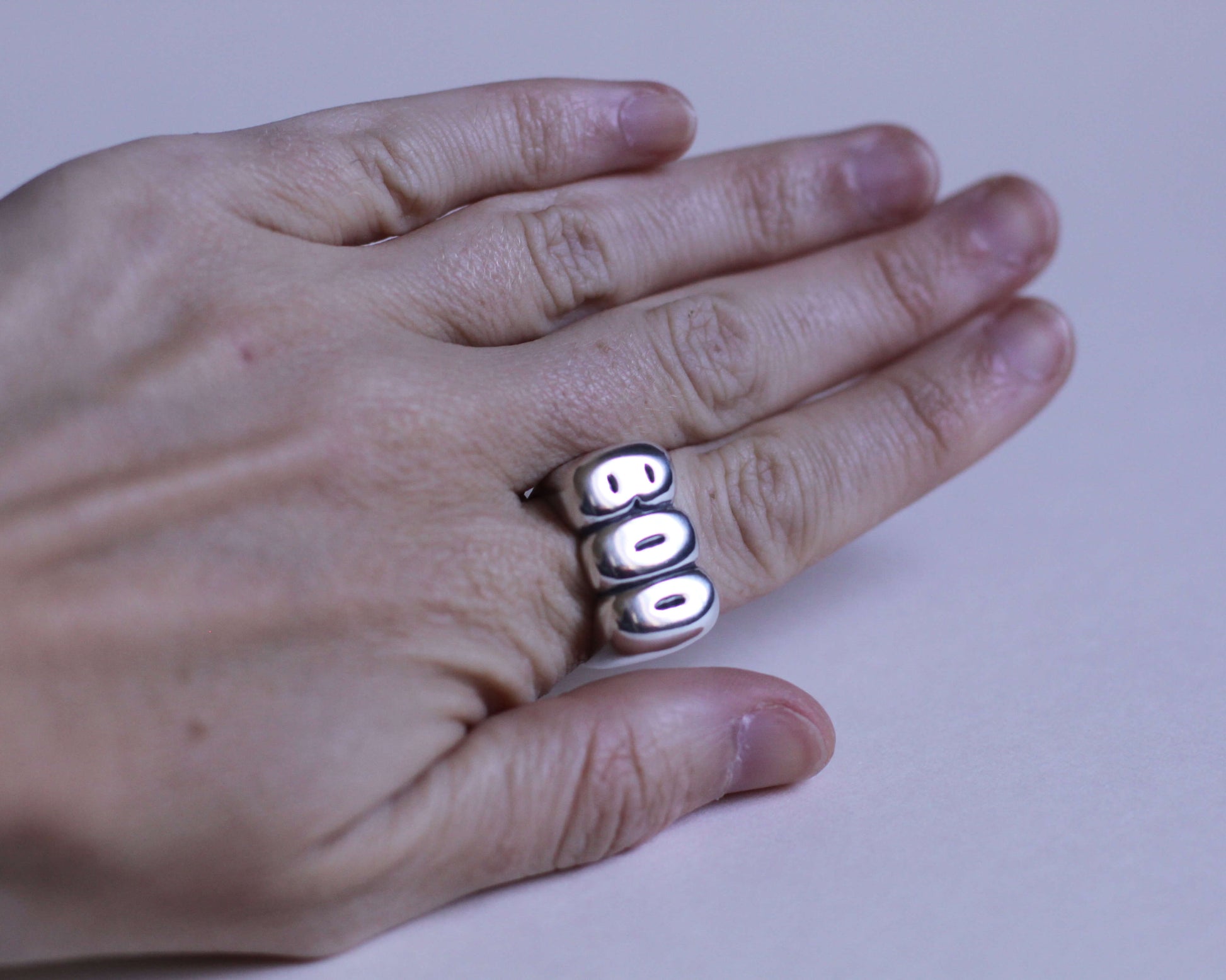 bague en argent massif reprenant le mot "BOO" portée au doigt