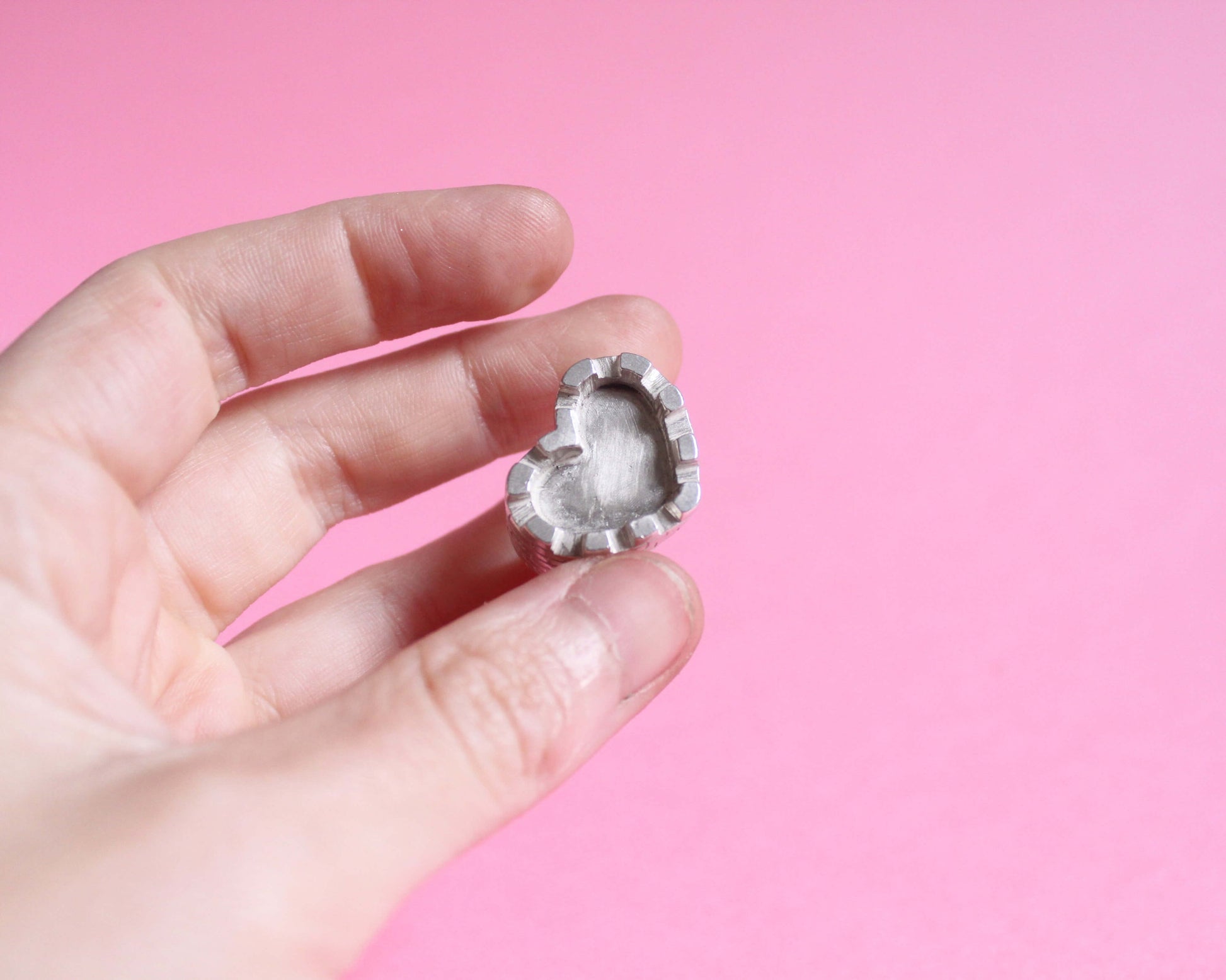 une main tient une bague en argent représentant un château fort en forme de coeur