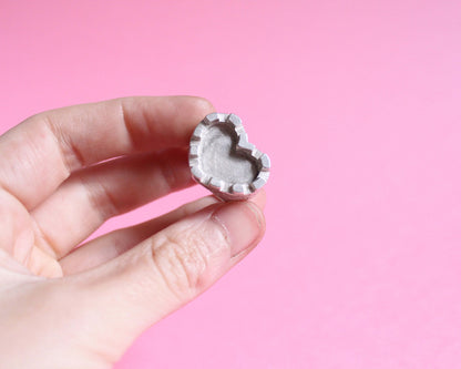 bague en argent massif symbolisant un château fort en forme de coeur tenue a la main