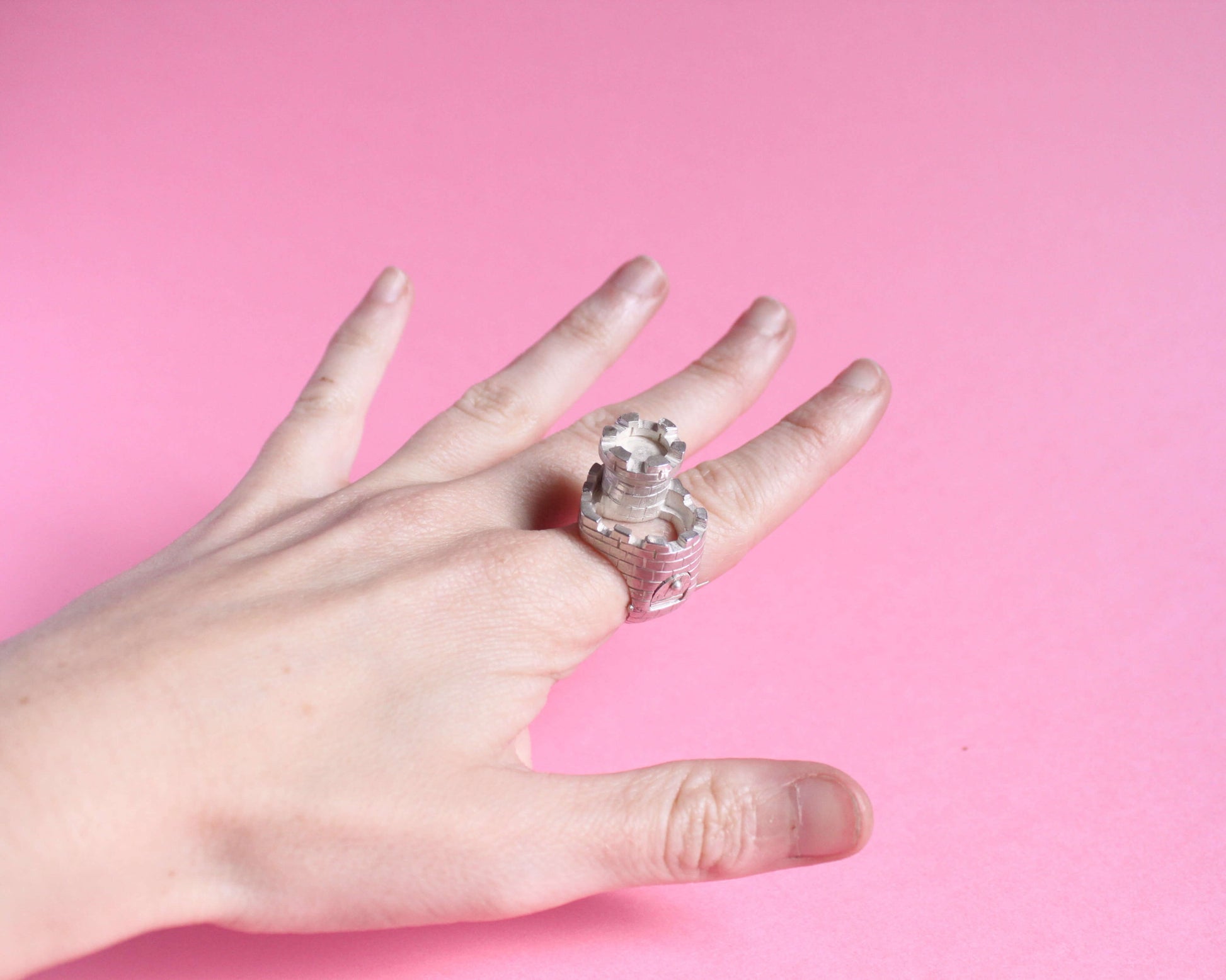 vue en angle d'une bague en argent en forme de château fort avec une tour