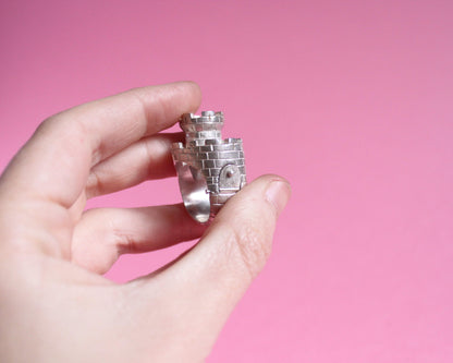 bague en forme de château fort avec une tour et un pont levis vue de près