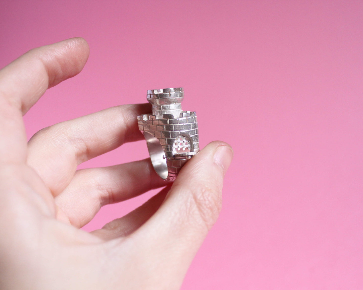 vue détaillée d'une bague en argent représentant un château fort en forme de coeur avec un pont levis ouvert et une herse