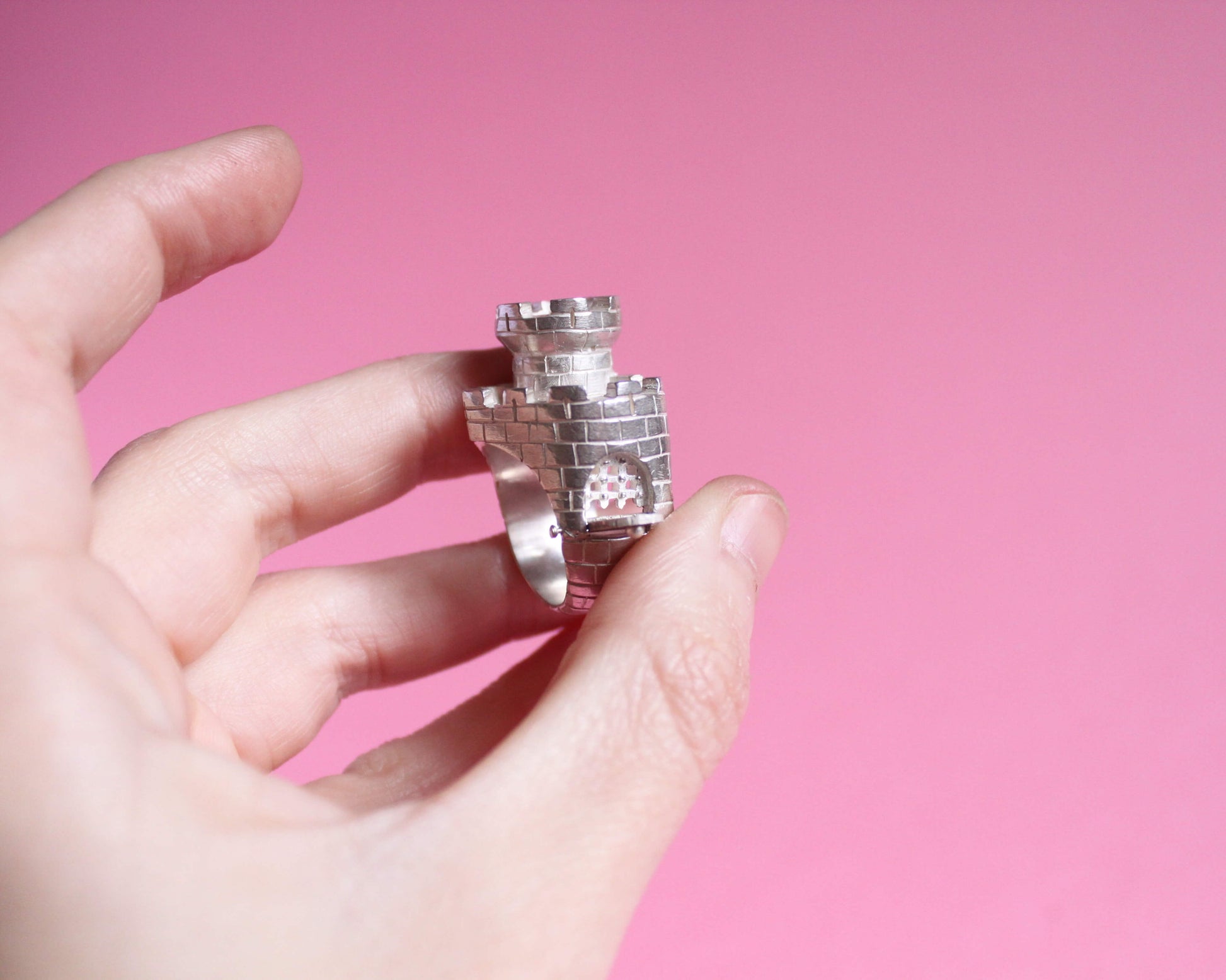 vue détaillée d'une bague en argent représentant un château fort en forme de coeur avec un pont levis ouvert et une herse