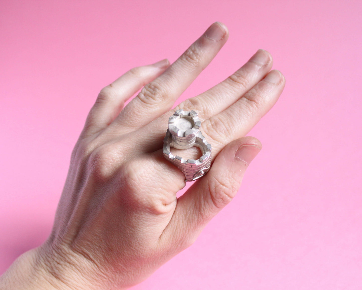 bague en argent massif symbolisant un château en forme de coeur avec une tour et un pont levis, portée au doigt