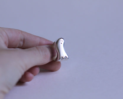 bague en argent en forme de fantôme avec un visage étonné tenue à la main