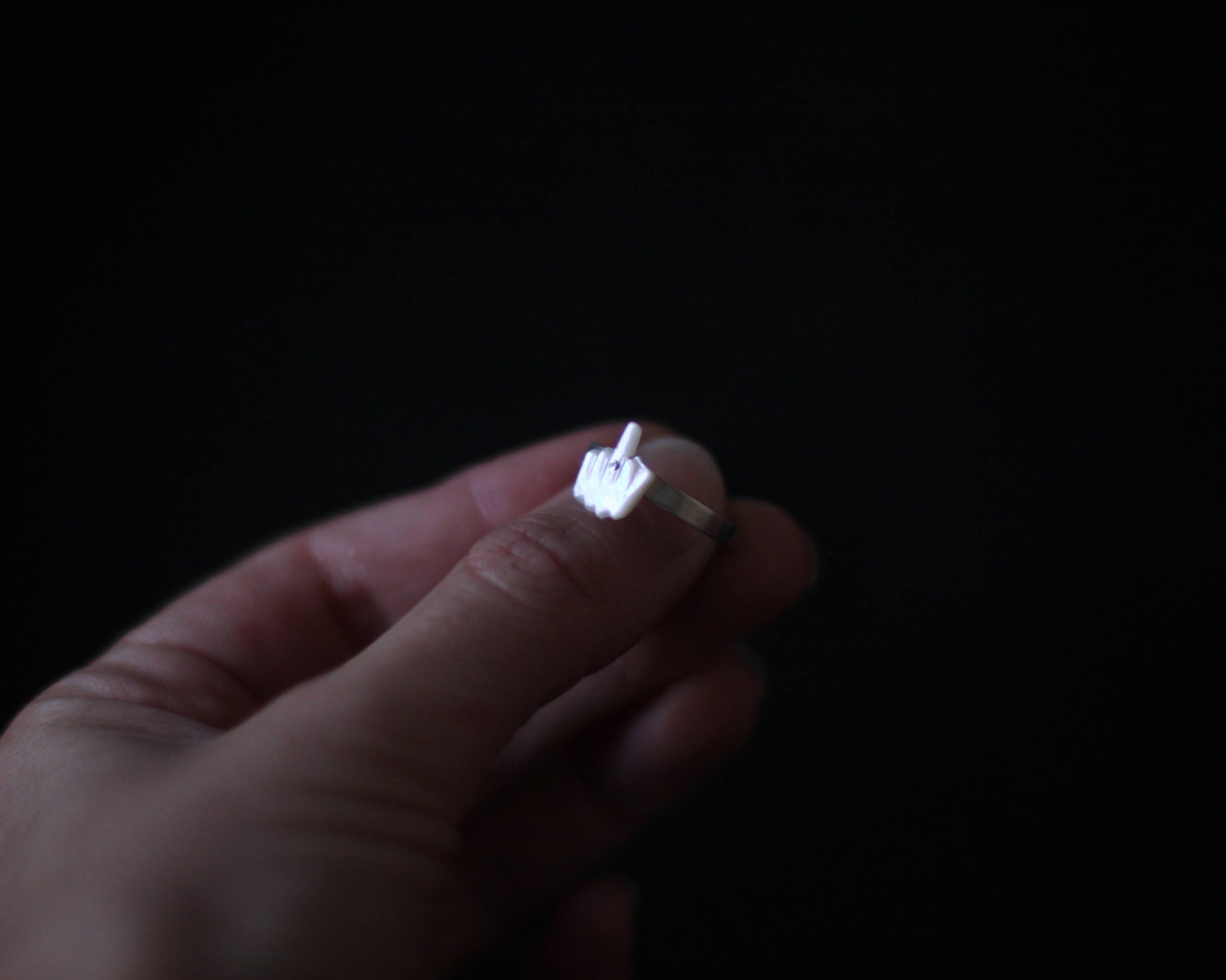 bague fine en argent comportant un élément en nacre représentant un doigt d'honneur