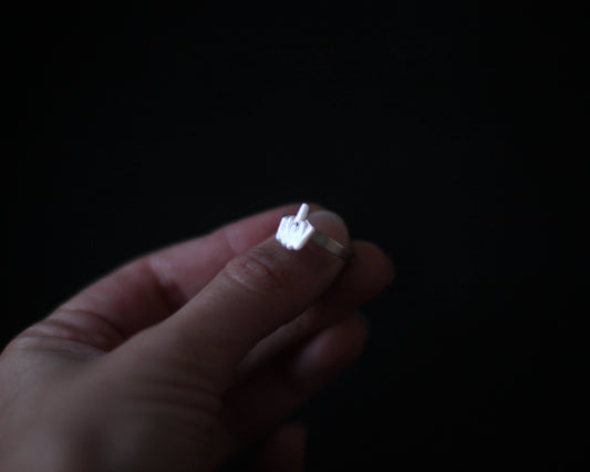 bague fine en argent comportant un élément en nacre représentant un doigt d'honneur