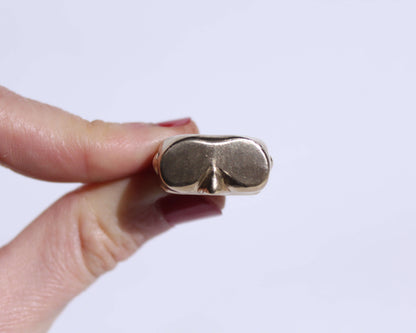 bague en laiton brut en forme de masque de plongée, tenue à la main