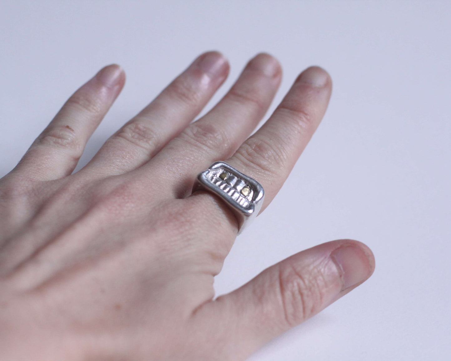 bague en argent massif représentant une bouche souriante avec deux dents en laiton