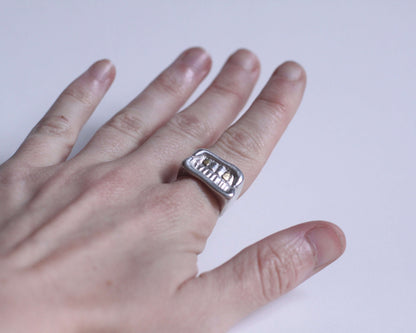 bague en argent massif représentant une bouche souriante avec deux dents en laiton