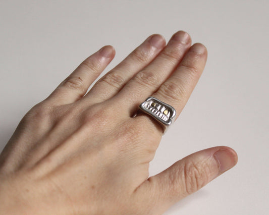 bague en argent massif en forme de bouche avec deux dents en laiton, portée au doigt