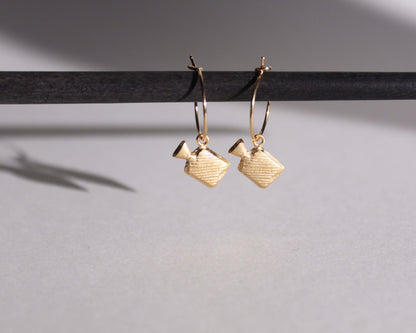 paire de boucles d'oreilles en laiton doré symbolisant des bouillottes, suspendues à des anneaux en laiton