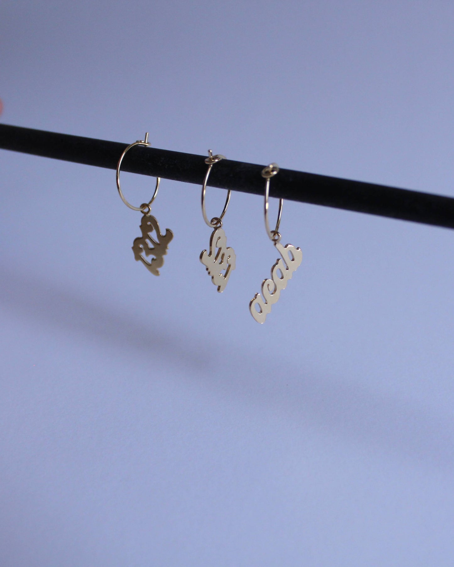 série de boucles d'oreilles en laiton doré portant le mot "acab" et le nombre "1312"