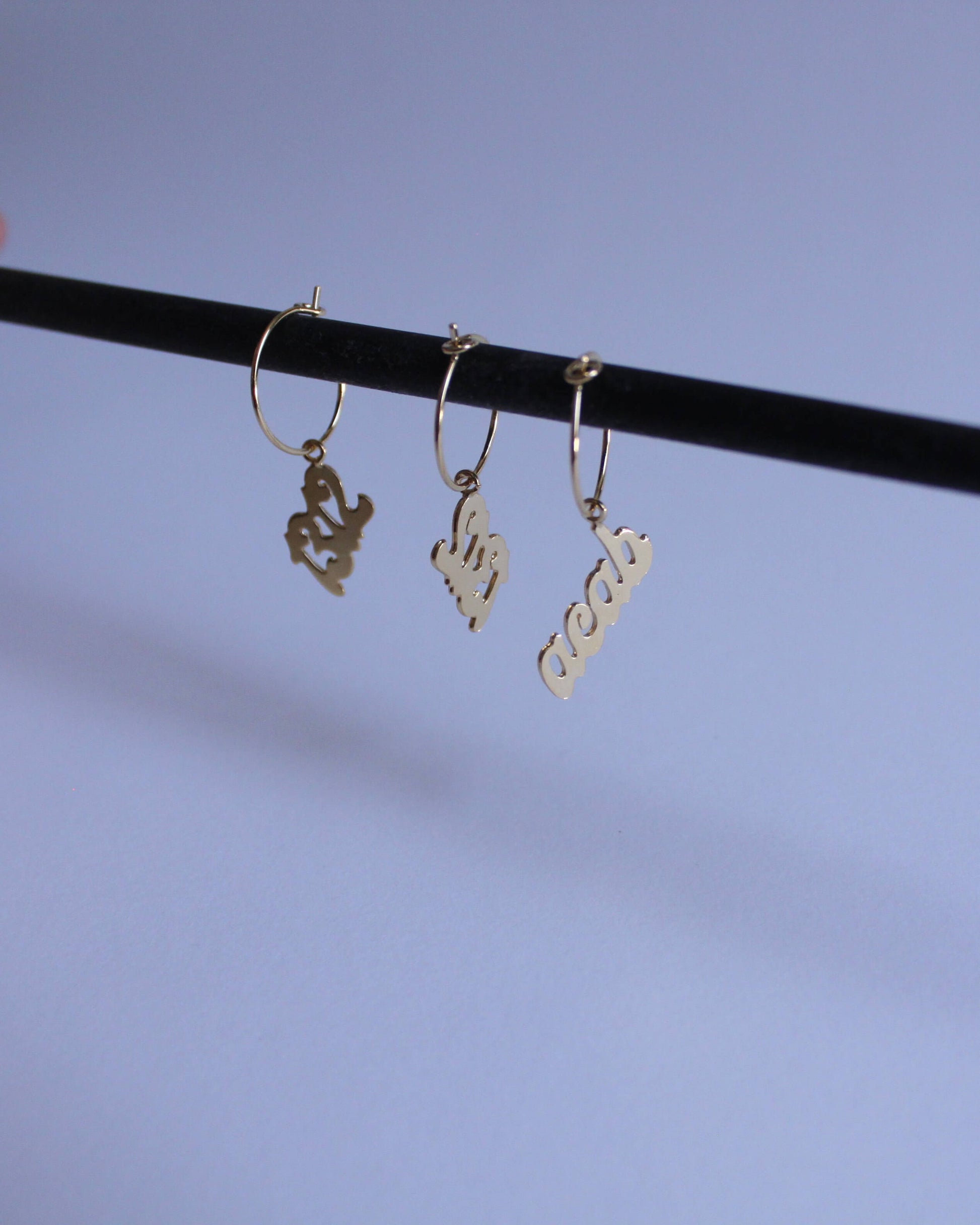 série de boucles d'oreilles en laiton doré portant le mot "acab" et le nombre "1312"