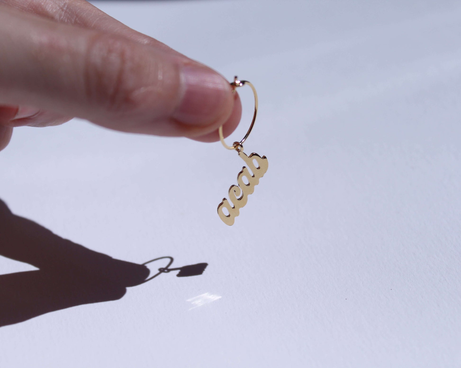 boucles d'oreilles en laiton doré représentant le mot "ACAB"