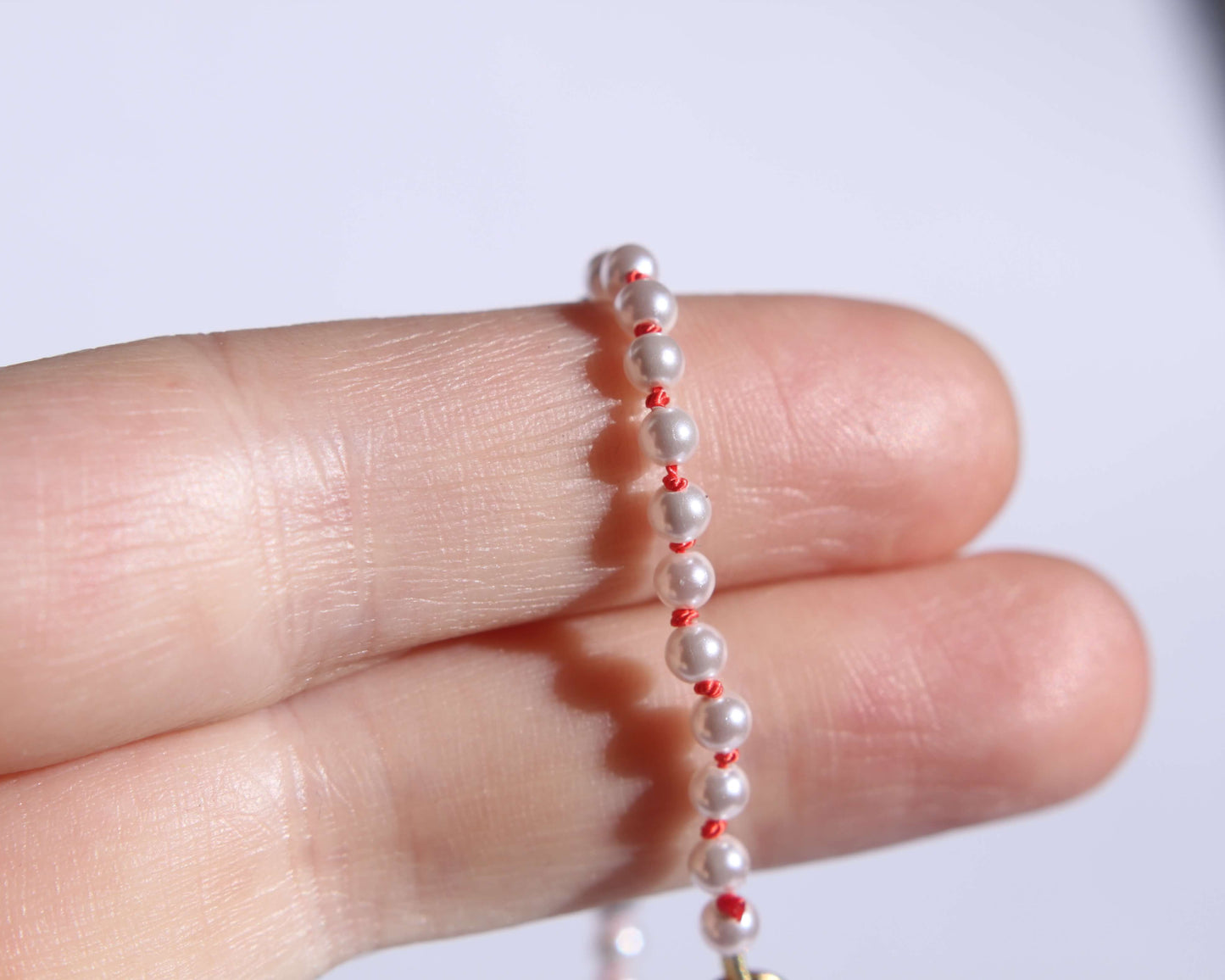 Collier en perles avec noeuds en fil de soie orange tenu sur deux doigts