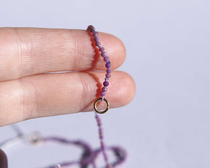 Bout du collier en perles en phosphosiderite facetté anneau tenu sur deux doigts