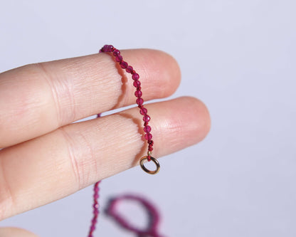 Bout du collier en perles en rubis chauffé facetté anneau tenu sur deux doigts