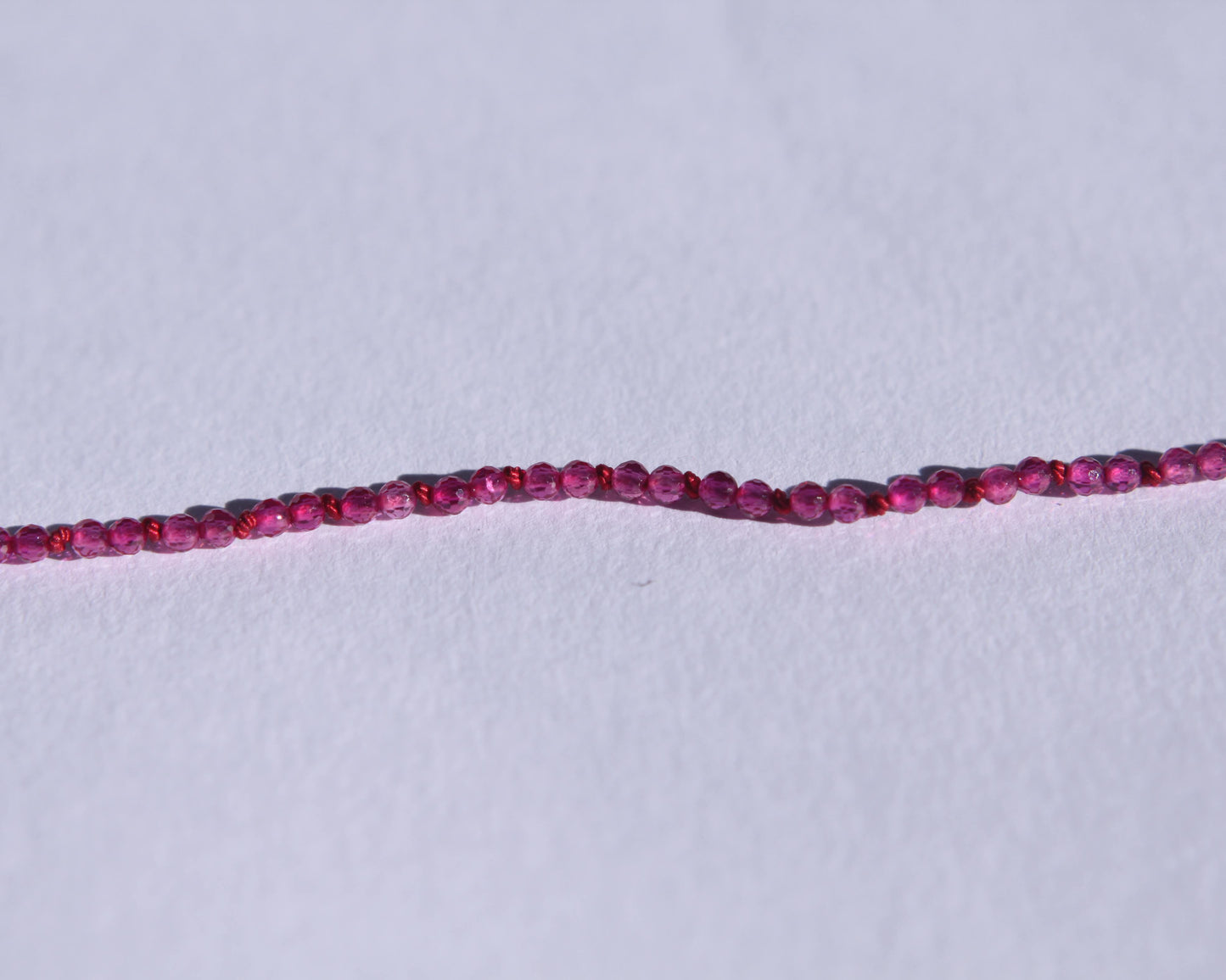 Zoom sur les perles en rubis facetté et les noeuds du fil de soie