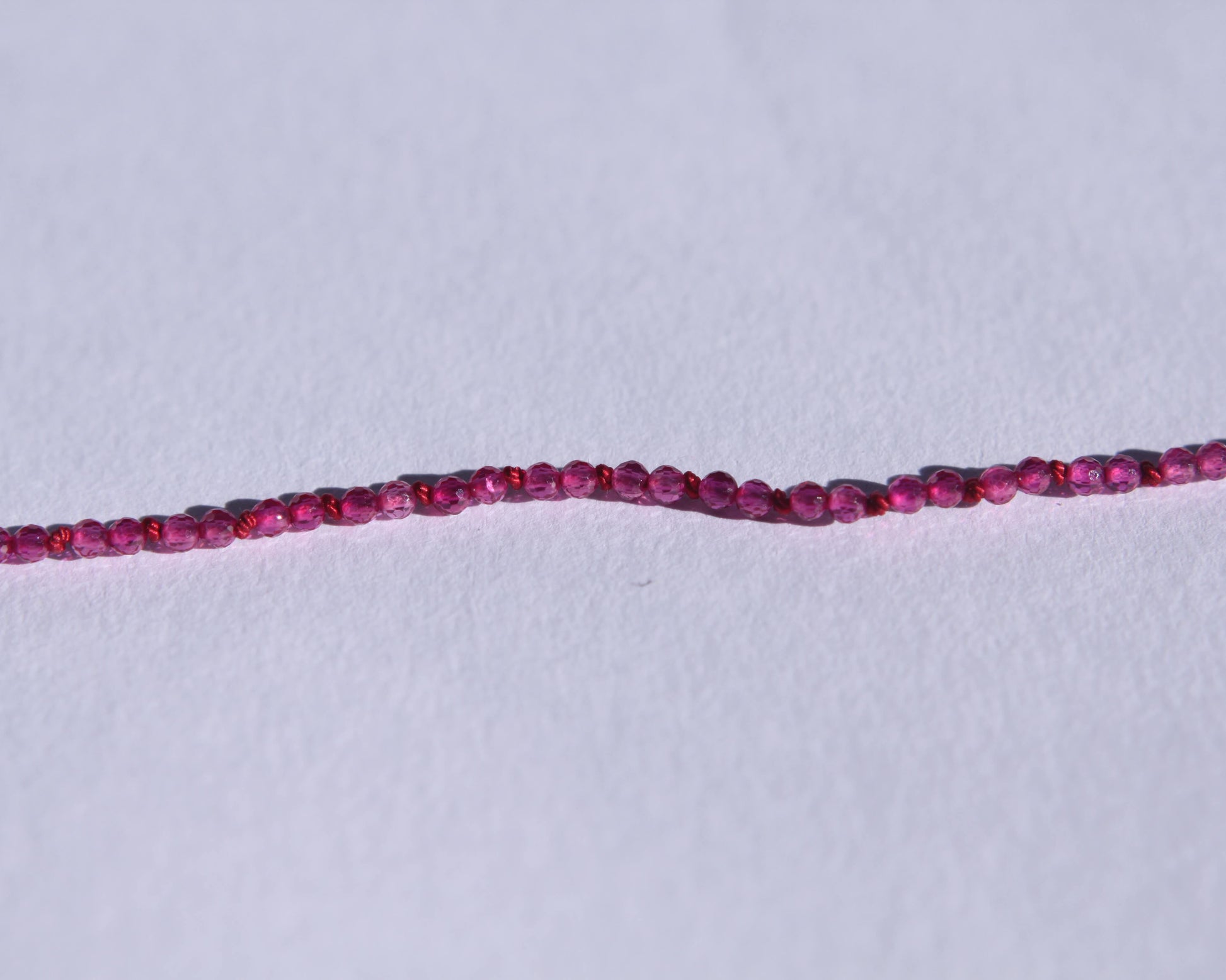 Zoom sur les perles en rubis facetté et les noeuds du fil de soie