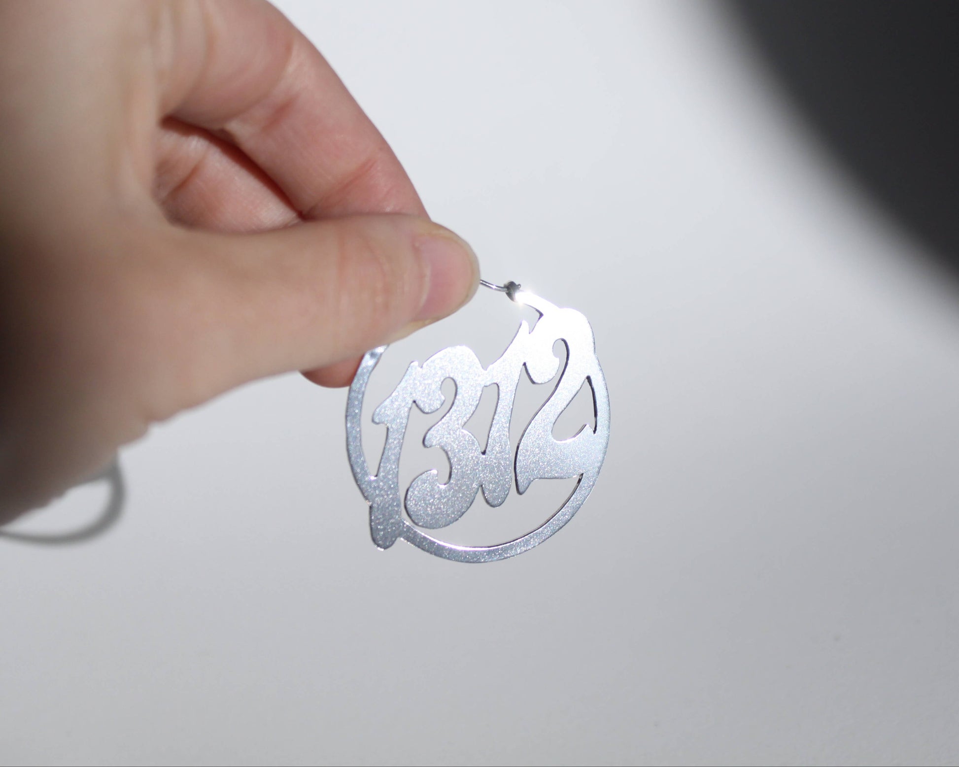 vue détaillée d'une boucle d'oreille en laiton plaqué argent symbolisant le nombre 1312