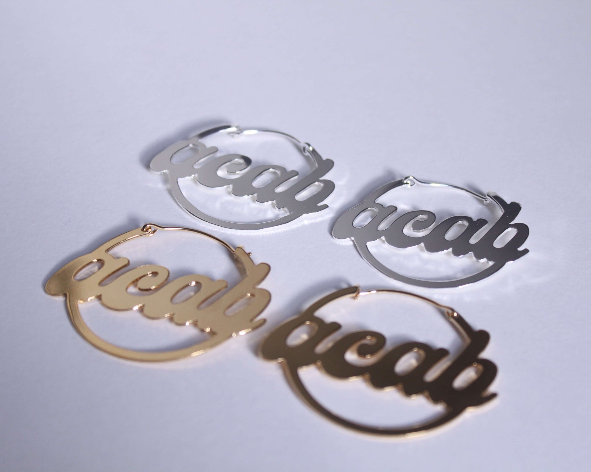 boucles d'oreilles en laiton plaqué argent et en laiton doré représentant le mot "ACAB" vues du dessus