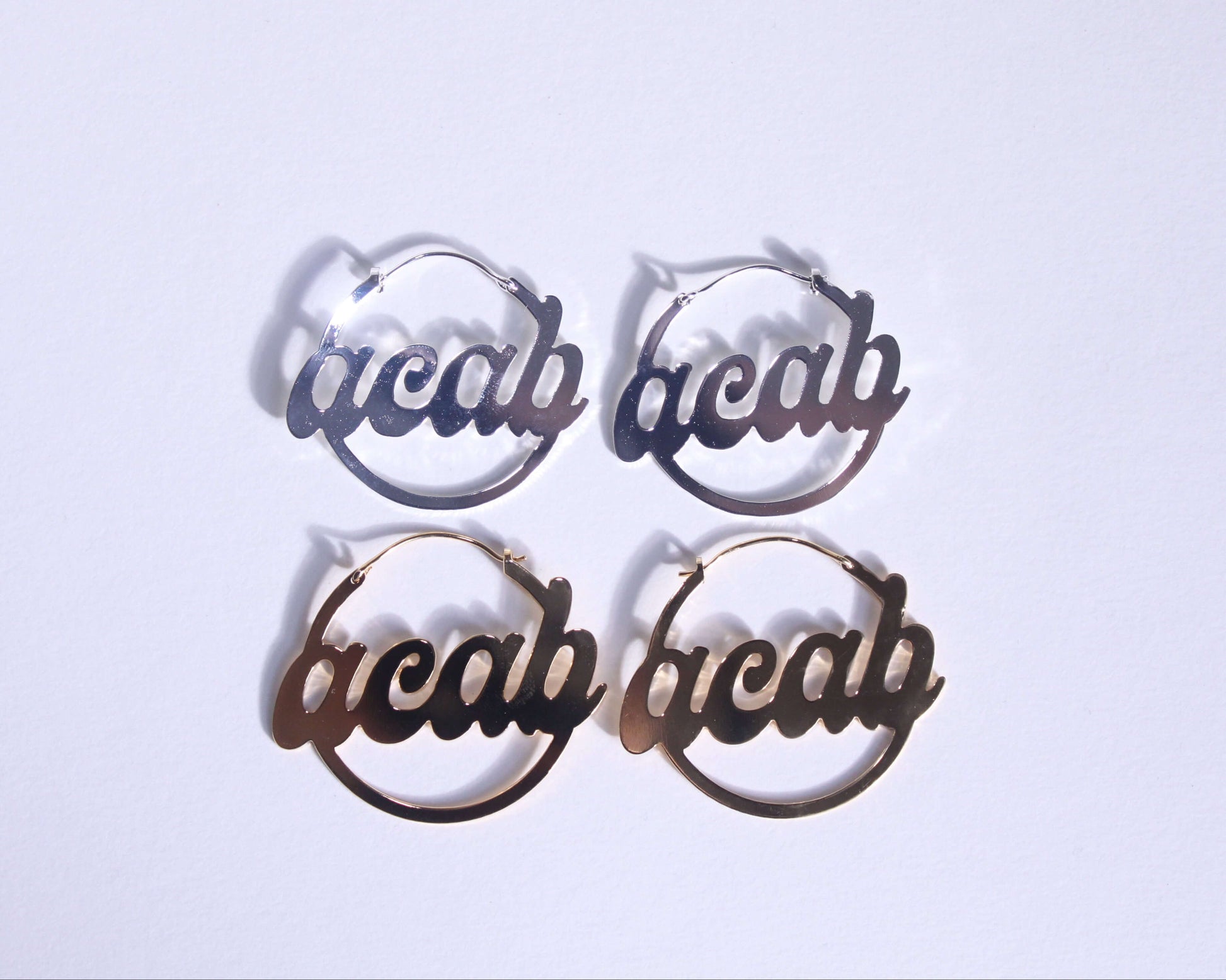 paires de créoles en laiton doré et en laiton plaqué argent portant la mention "ACAB"