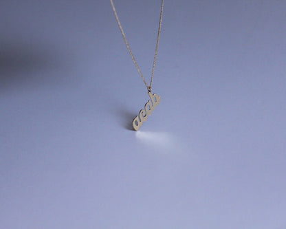 collier avec un pendentif en laiton doré portant le mot "acab" dessus