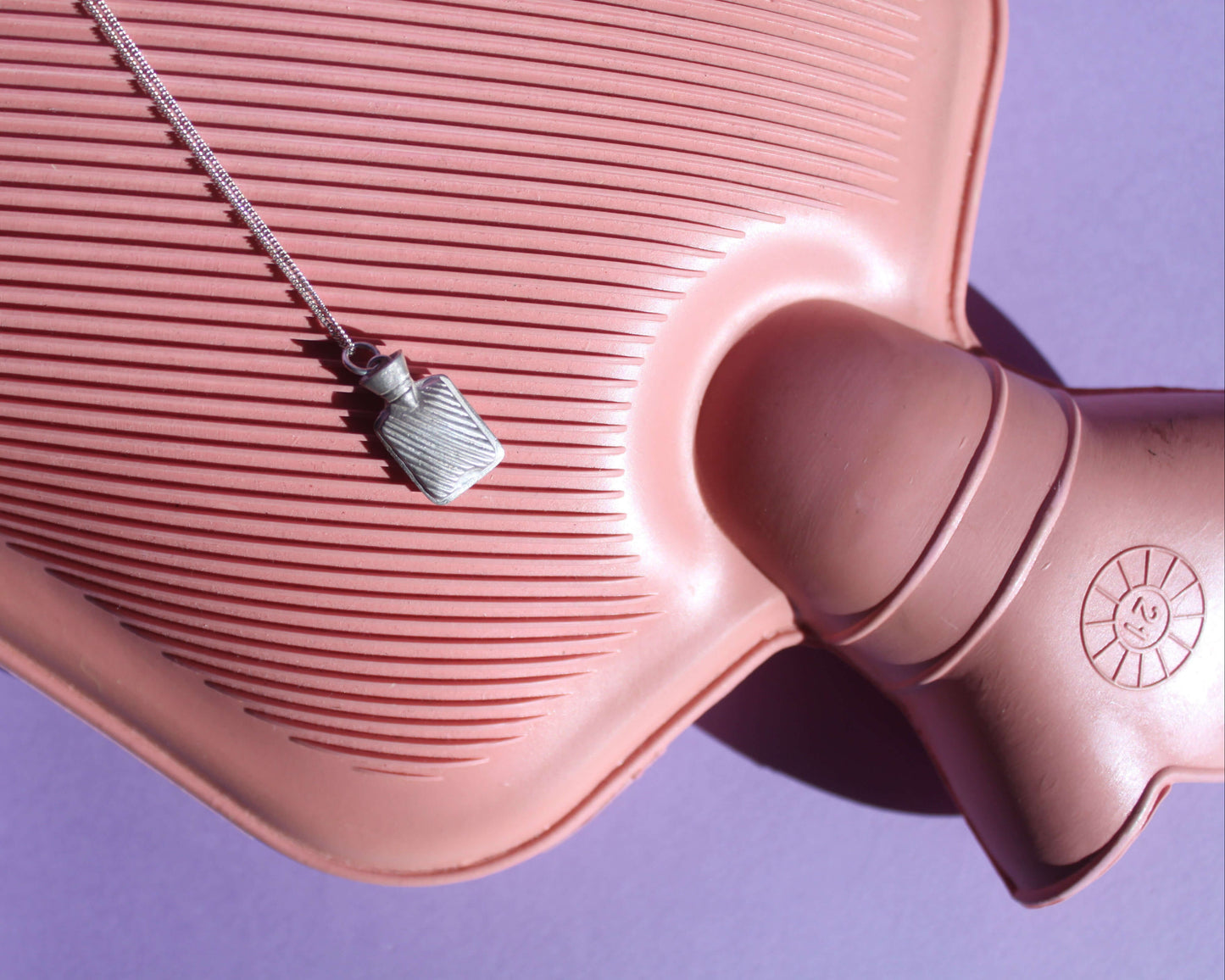 pendentif bouillotte en argent massif posé sur une bouillotte