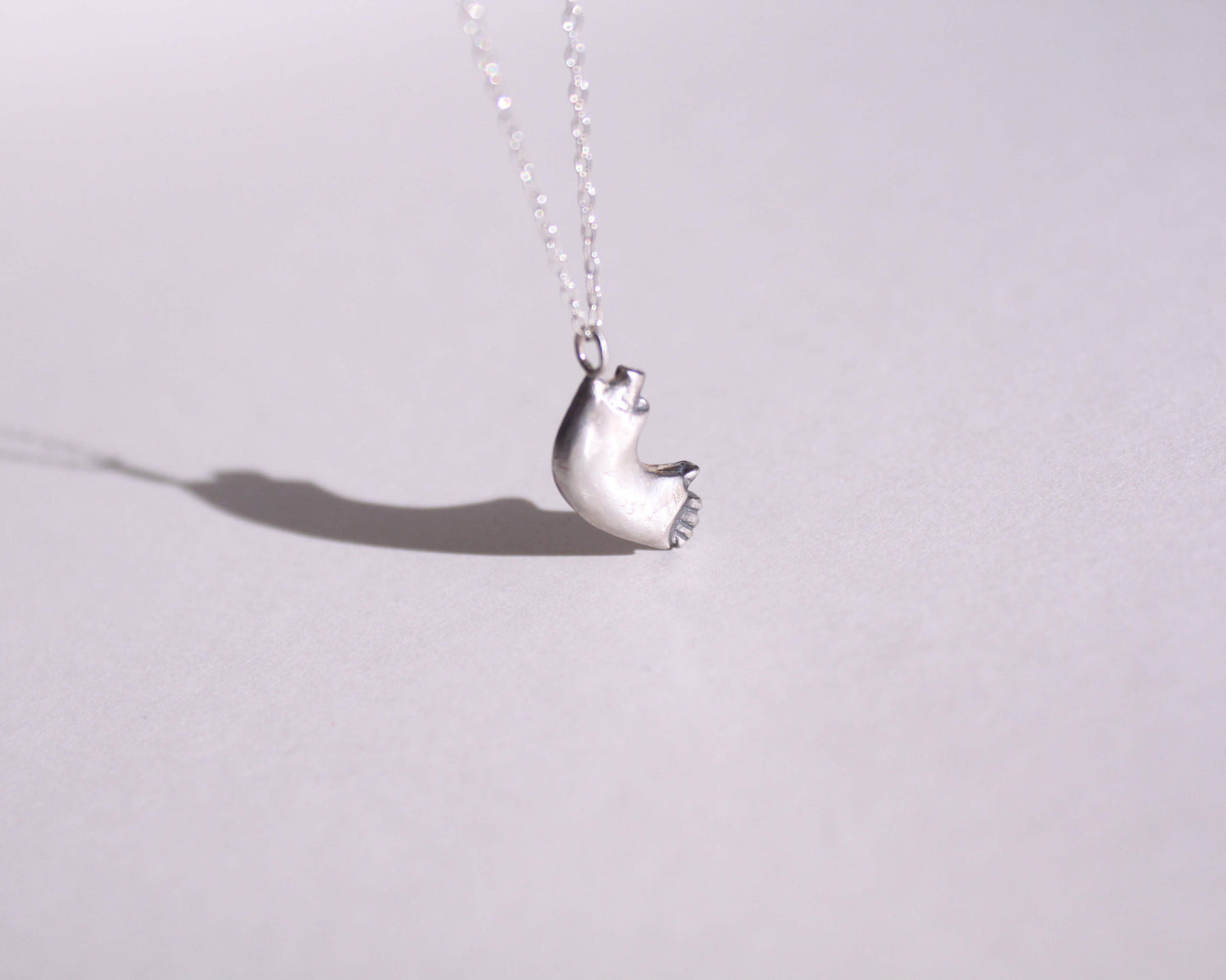 pendentif en argent massif en forme de bras cassé