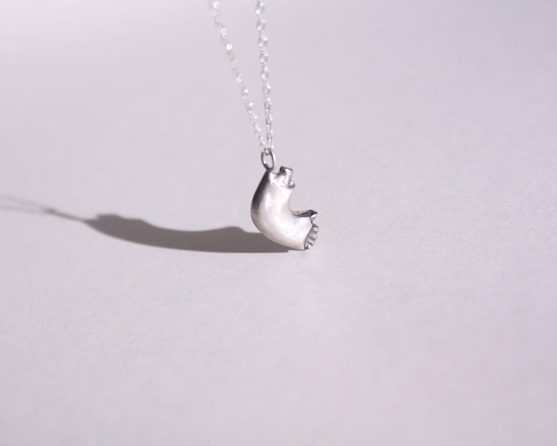 pendentif en argent massif en forme de bras cassé