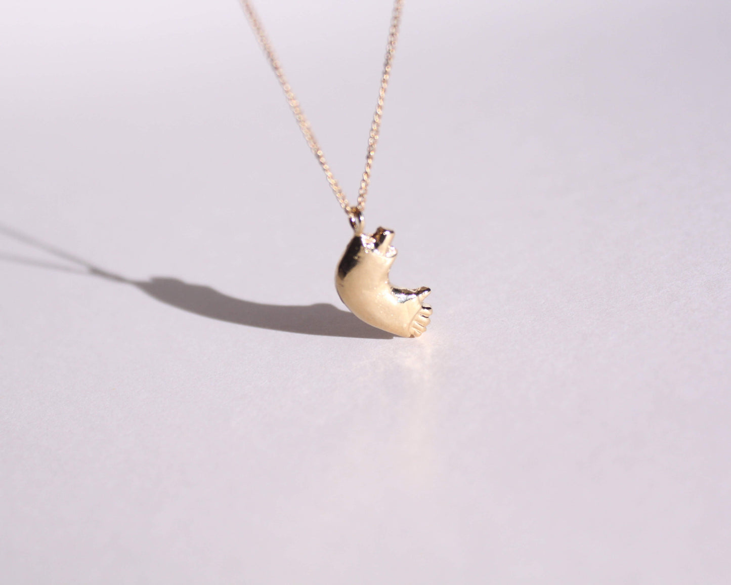 pendentif en laiton plaqué or représentant un bras cassé