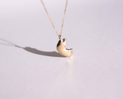 pendentif en laiton plaqué or représentant un bras cassé