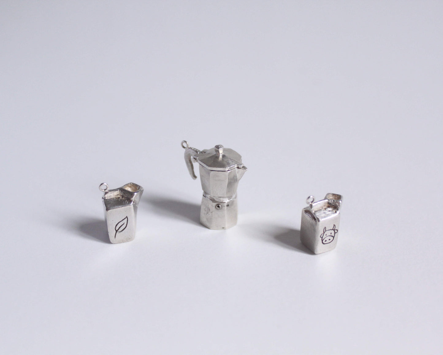 série de pendentifs en argent massif symbolisant des briques de lait et une cafetière italienne